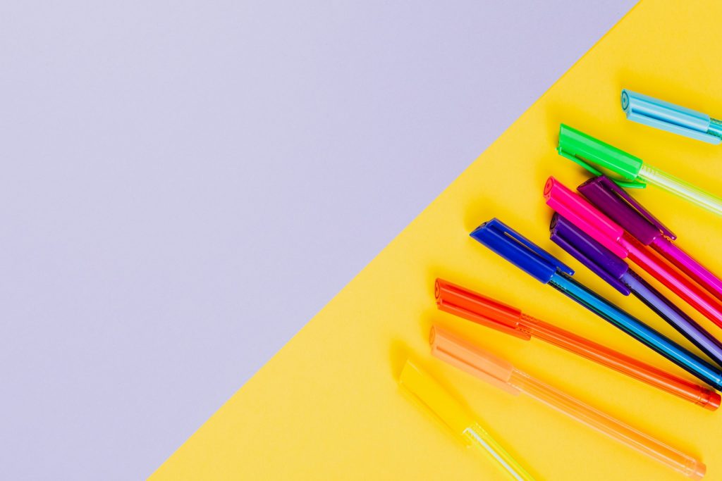 Different coloured pens on a yellow piece of paper